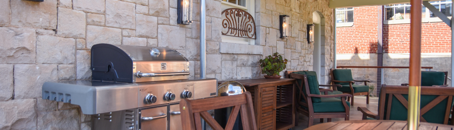 a grill and tables on the back porch of the Stone House