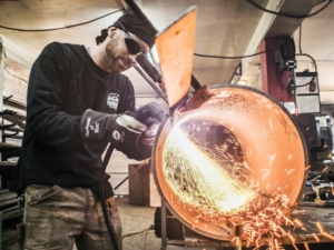 a man welding a cylndrical piece of metal