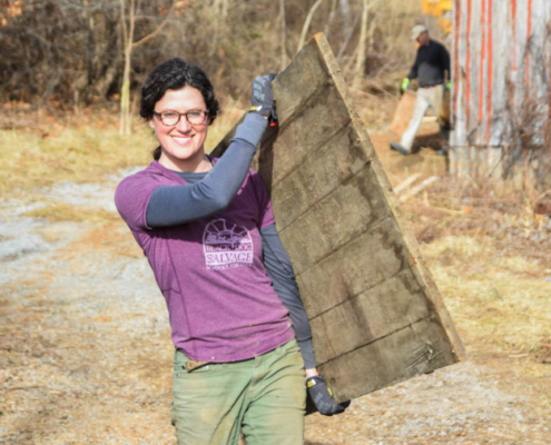 Grayson Goldsmith carries a piece of salvaged wood at the Taylor family farm